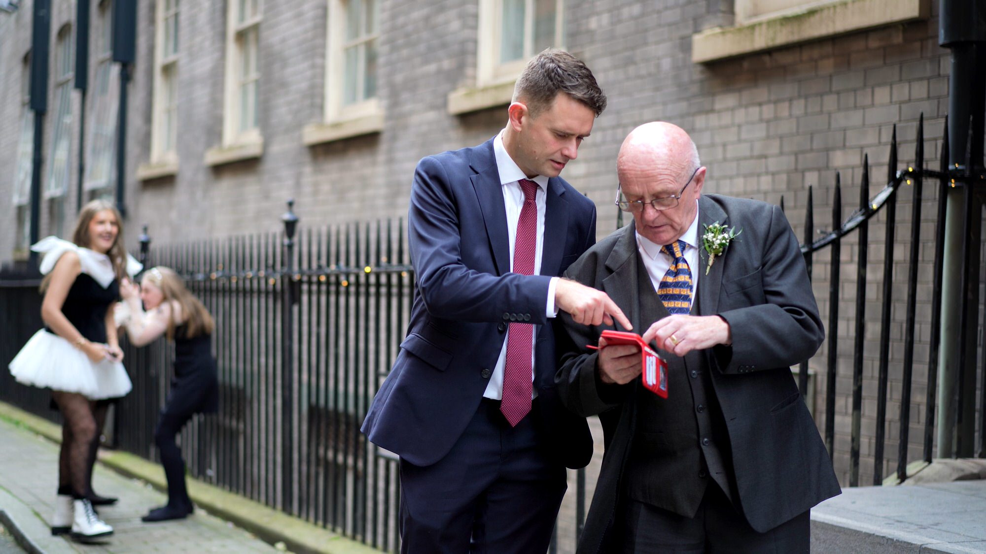 a wedding guest helps an older guest take a phone photo