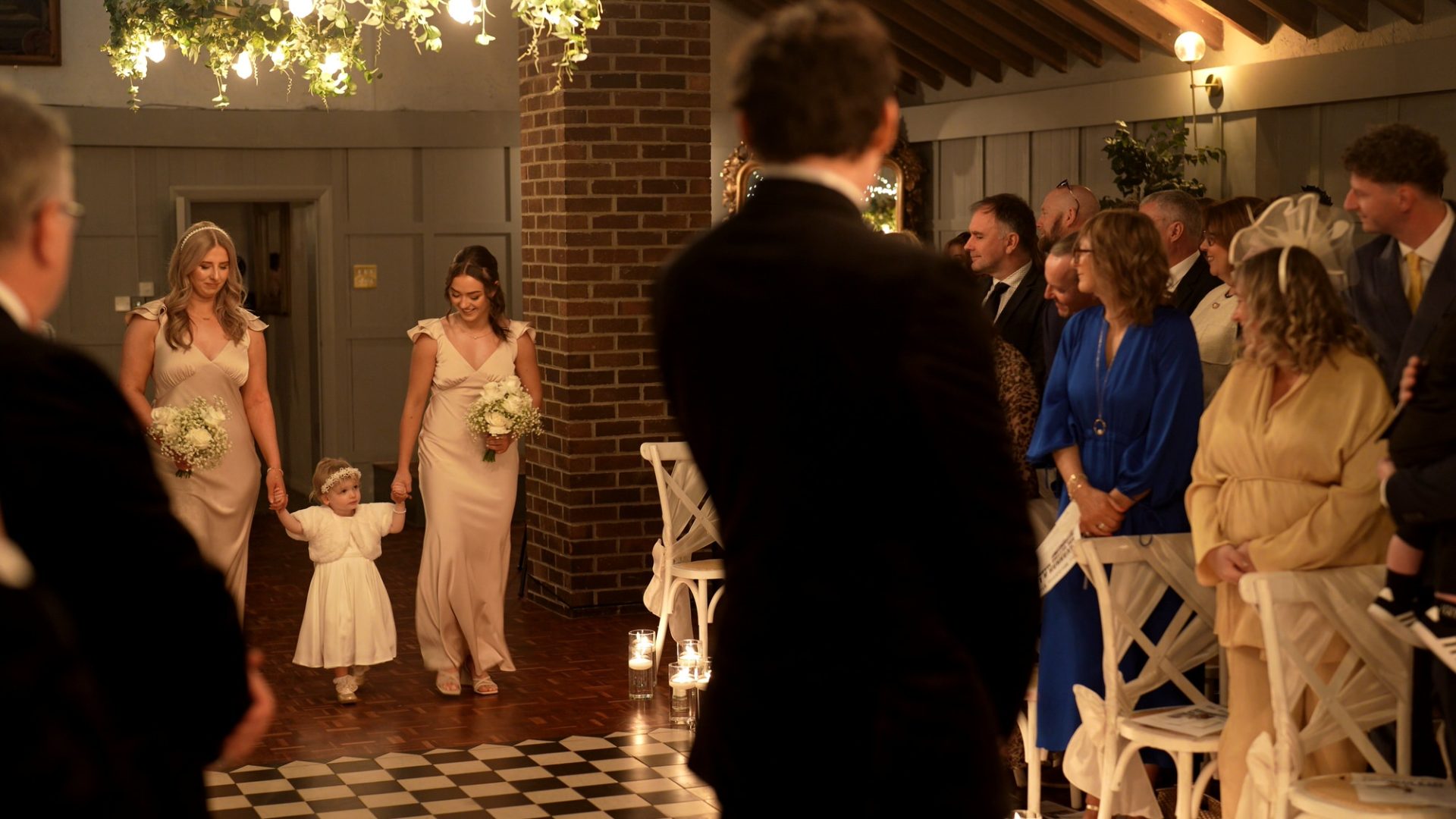 a flower girl and bridesmaids walk down the aisle