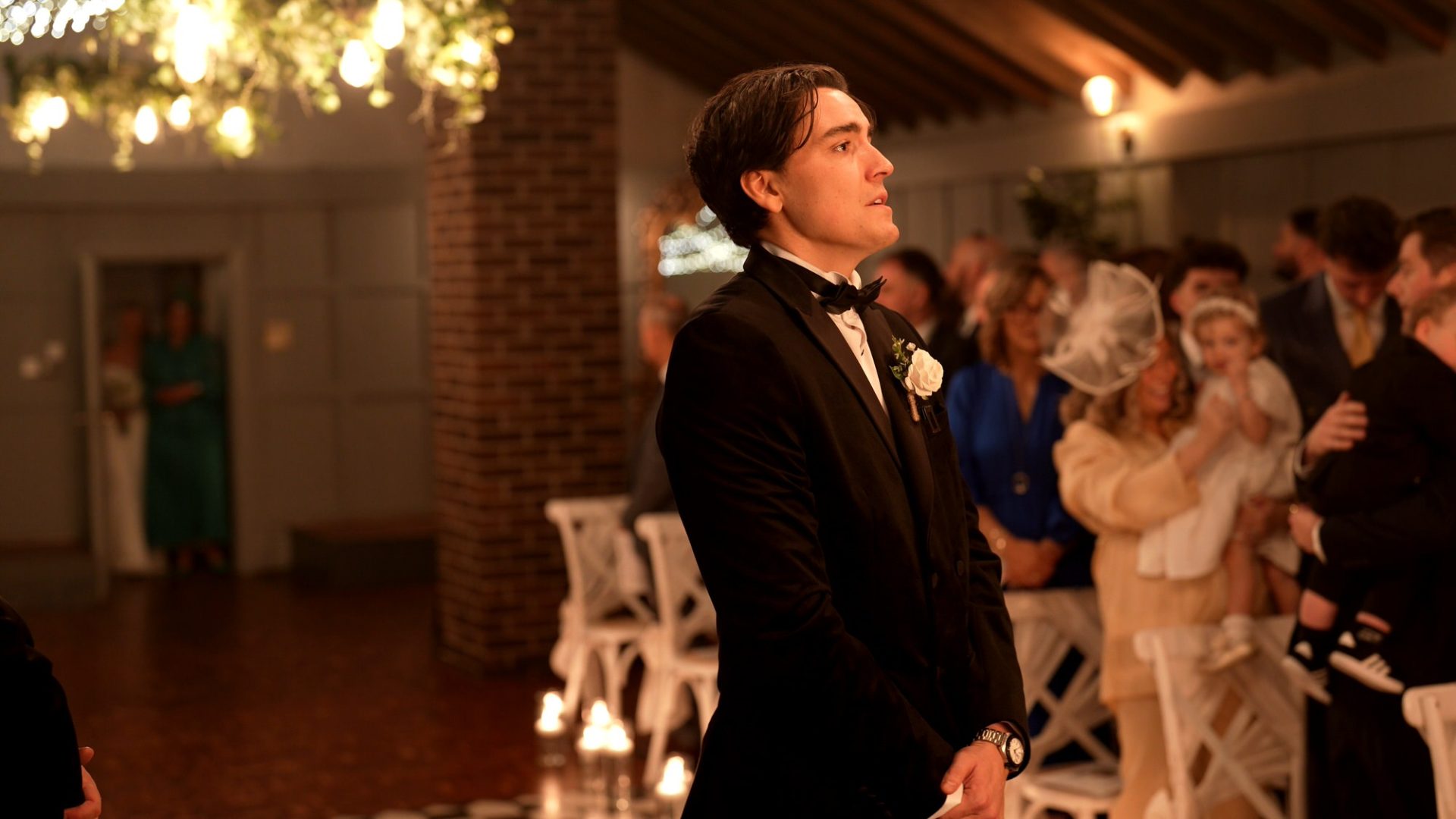 an emotional groom in a black tux takes a deep breath before the bride walks down the aisle at Larkspur Lodge in Knutsford