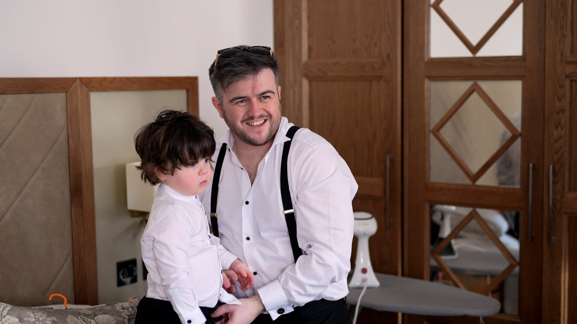a groomsman laughs with his son getting ready in Cheshire