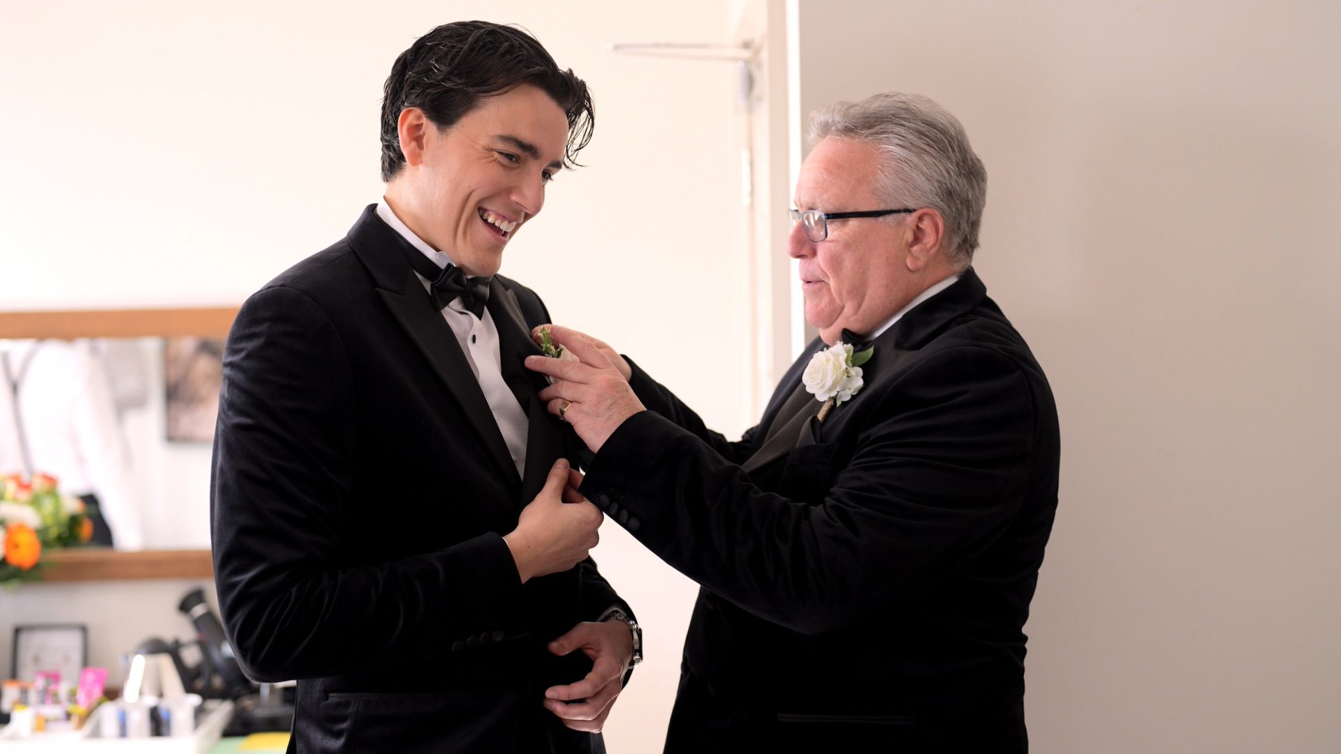 a dad helps his son the groom with his black bowtie at Larkspur Lodge in Cheshire
