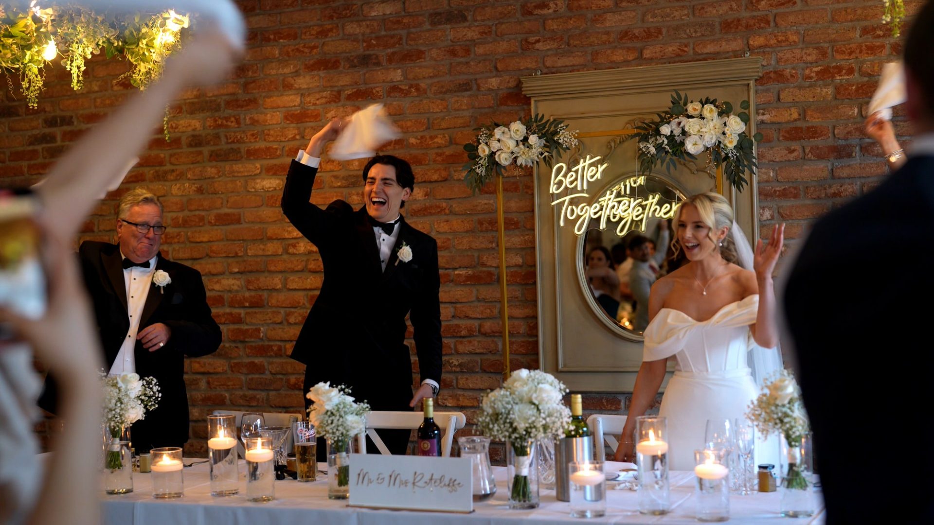 a groom waves his napkin around with guests during a fun black tie wedding at Larkspur
