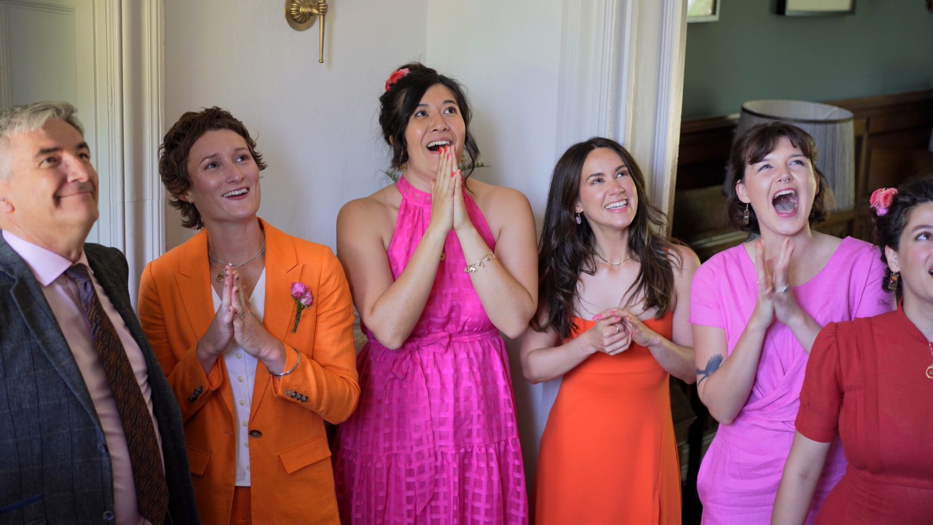 bridesmaids wearing bright dresses react to the bride before her Wyresdale wedding ceremony
