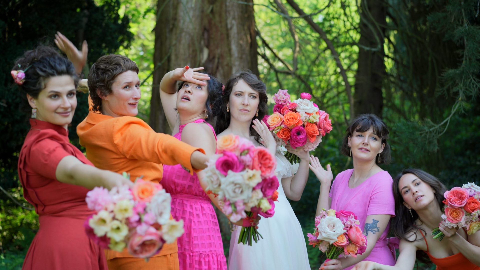 a bride and her bridesmaids with vibrant outfits do silly poses for photo and video