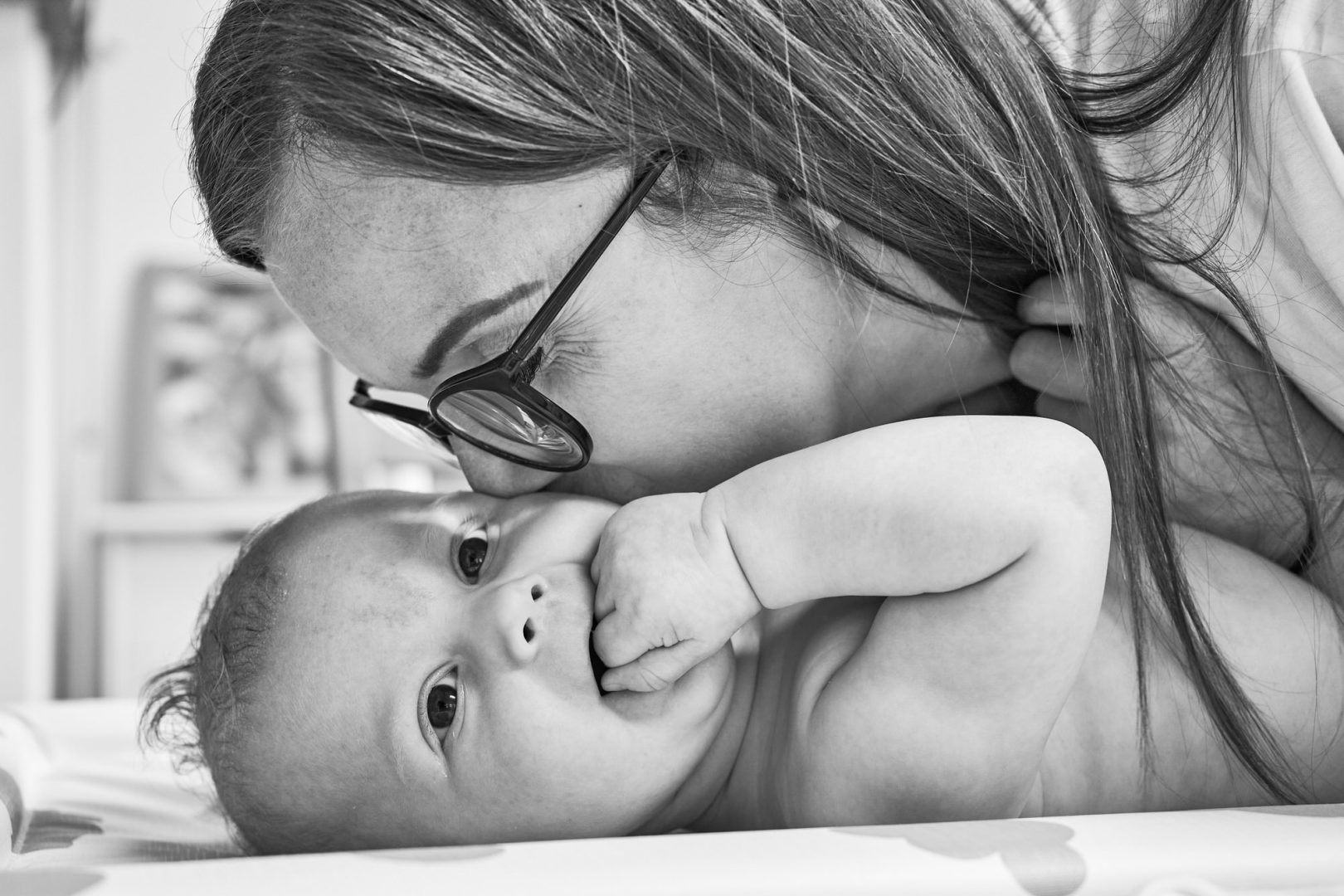 a mum nuzzles into a baby laying down on a changing mat