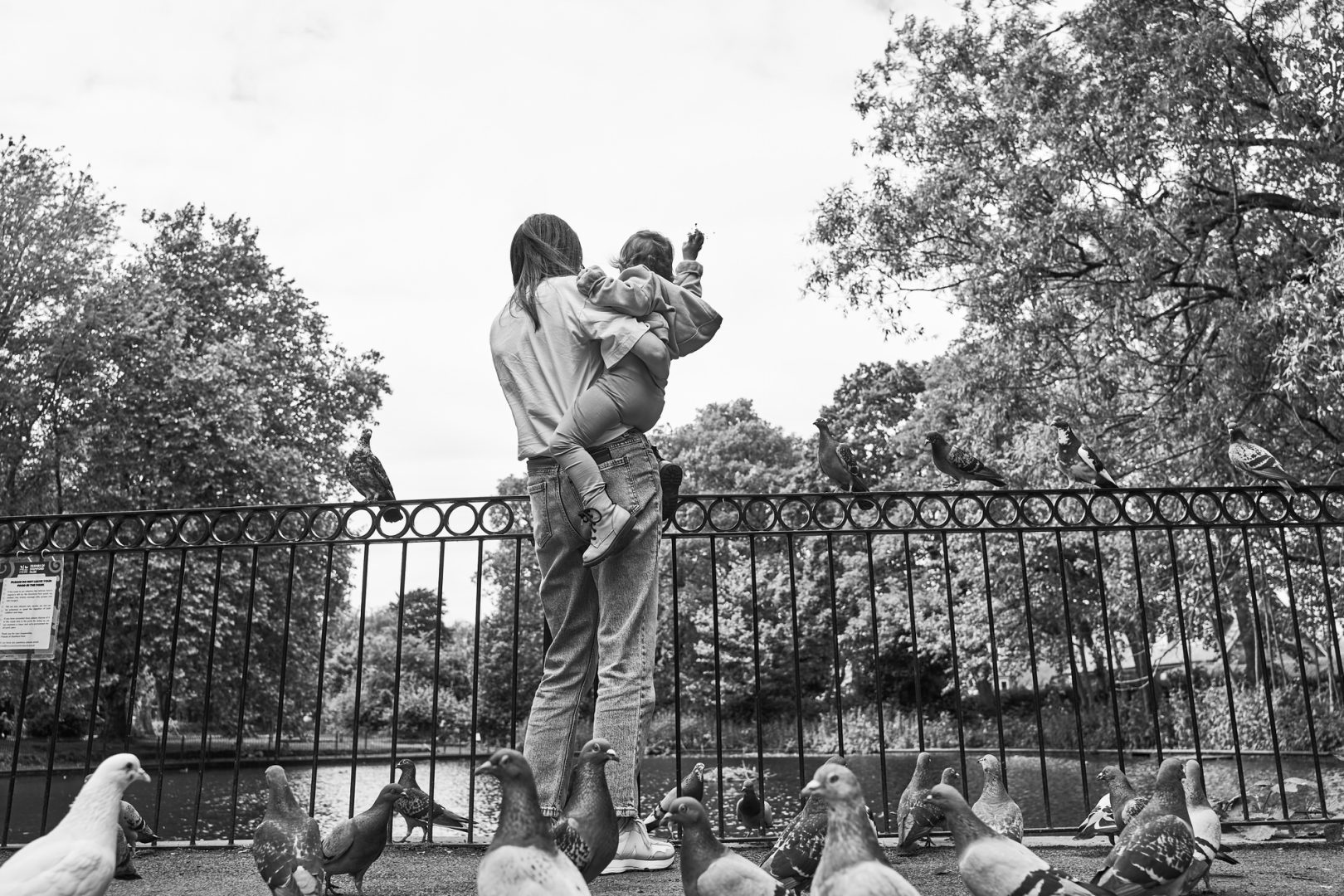 a mum and daughter feed the birds at the local park