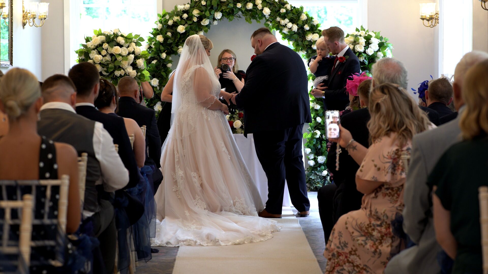 a couple exchange rings during an indoor ceremony at Statham Lodge Hotel in Cheshire