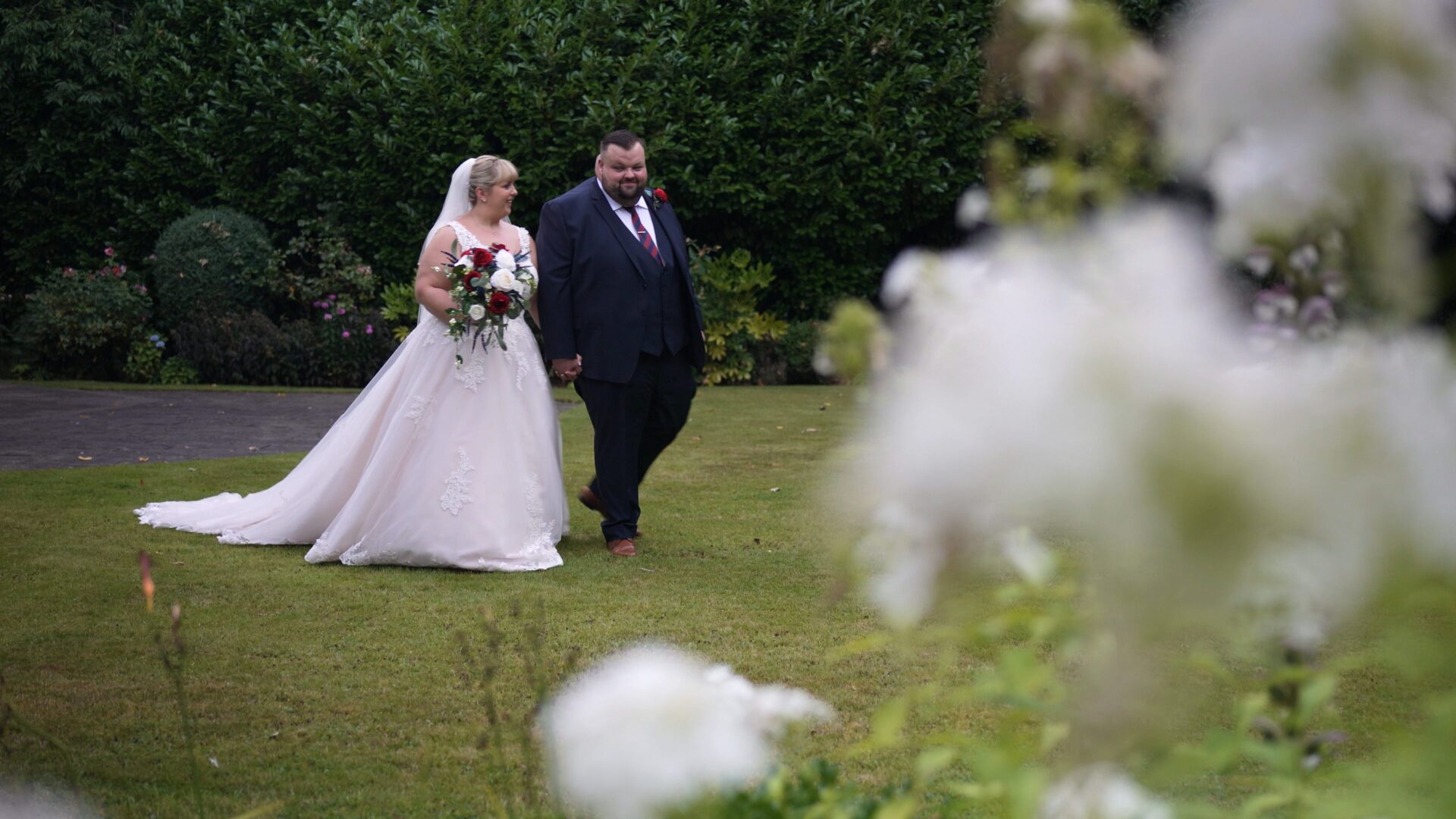 a bride and groom stroll through the private gardens natural wedding videography