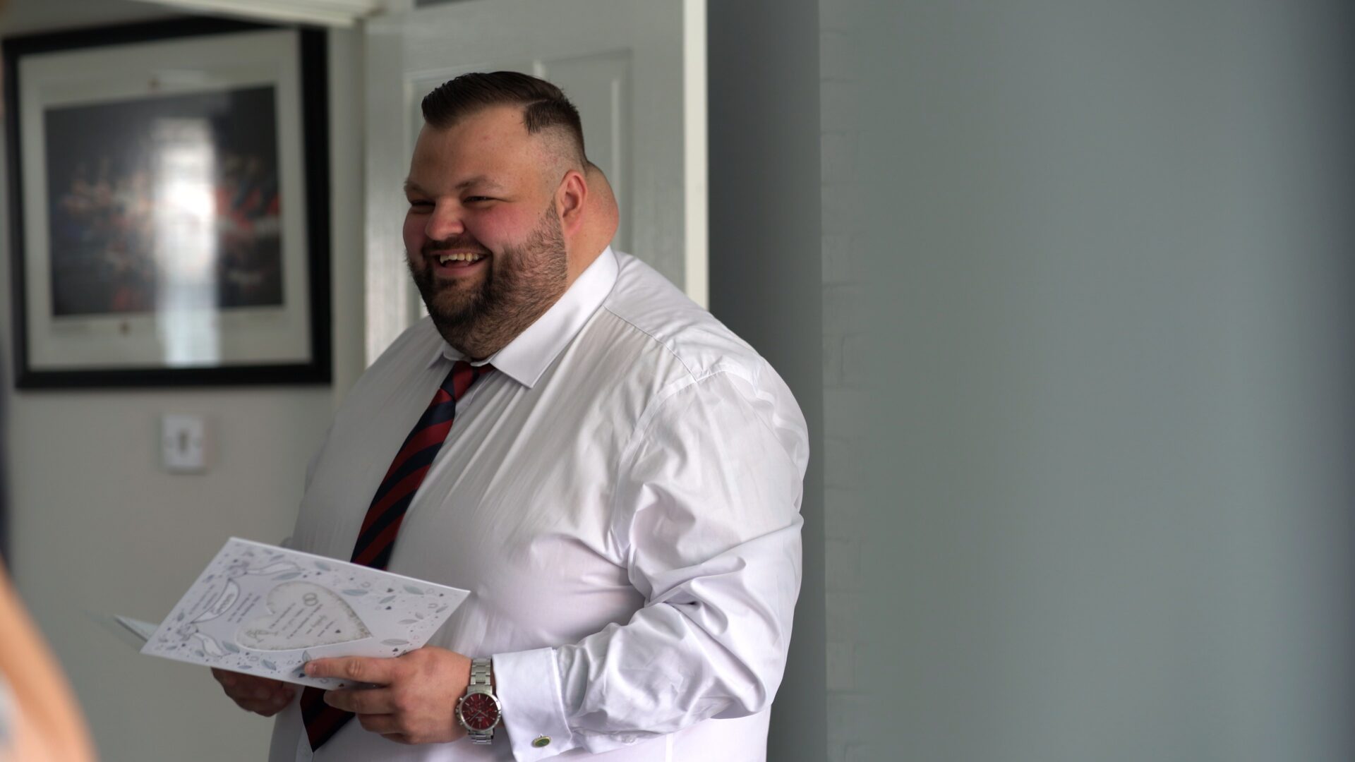 a groom laughs as he opens his wedding cards