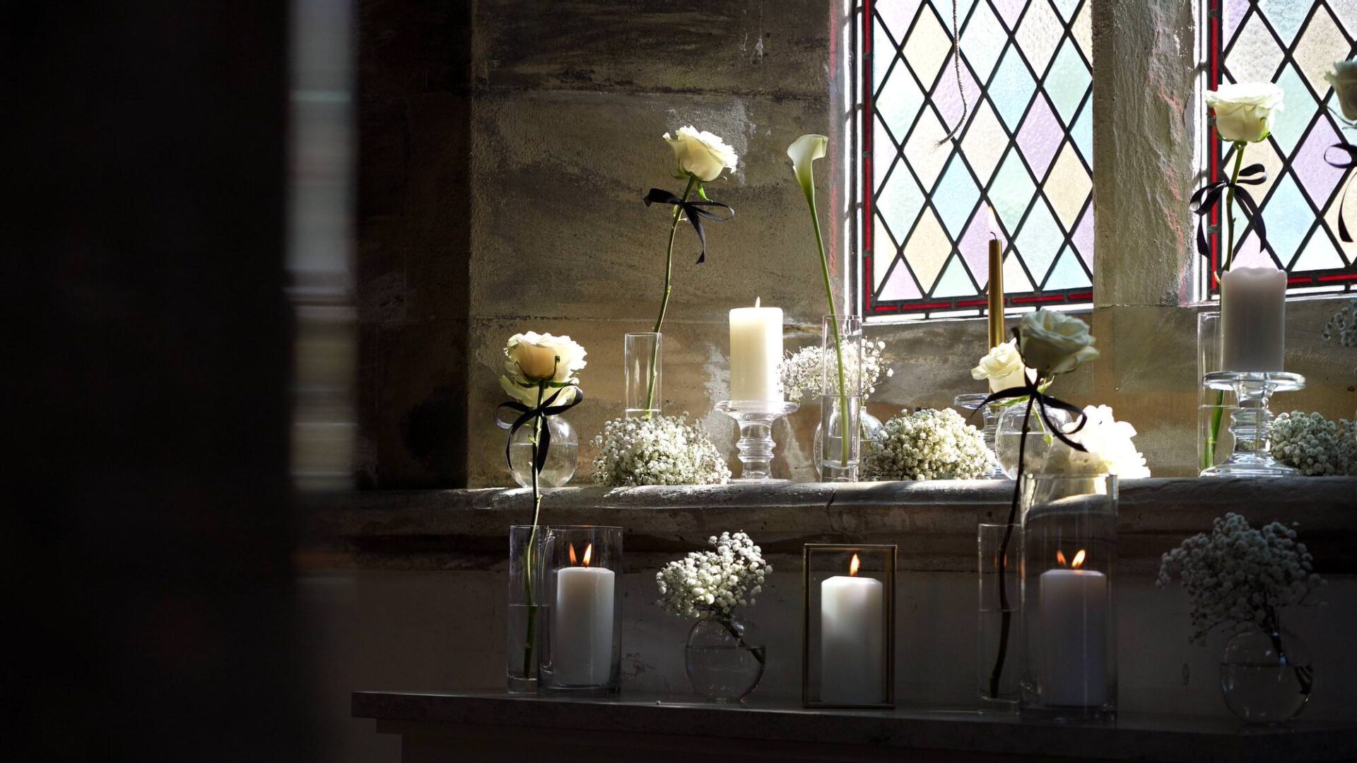 detail shot of classic white roses and candles in jars in Rudding Park Chapel