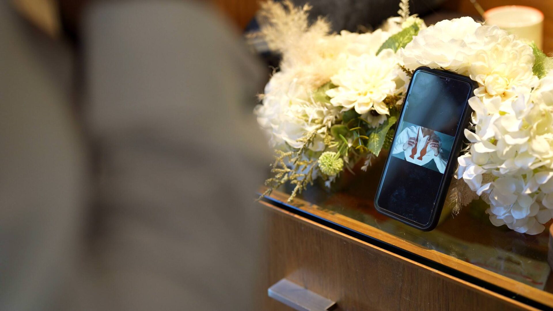 a detail shot of a groomsman following youtube to do his bowtie