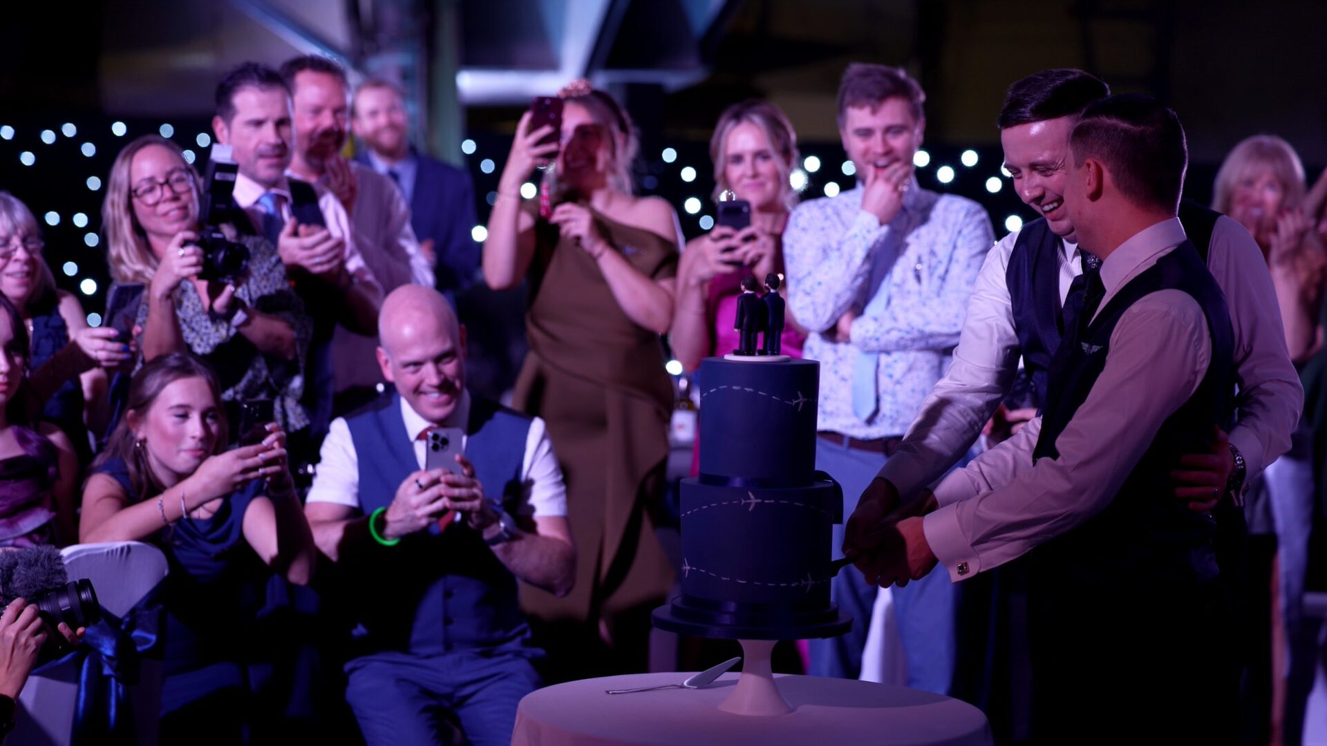 videographer captures a candid moment of guests photographing the cake cutting under Concorde Manchester