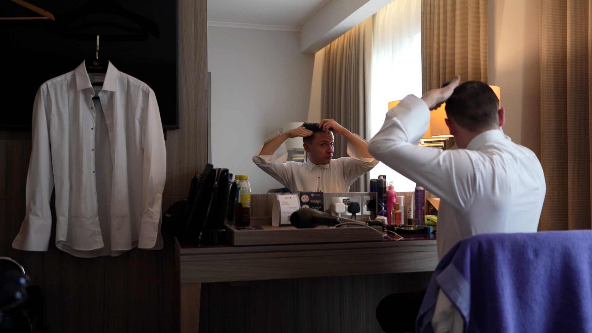 a groom sits in his chair at Radisson Manchester airport doing his hair