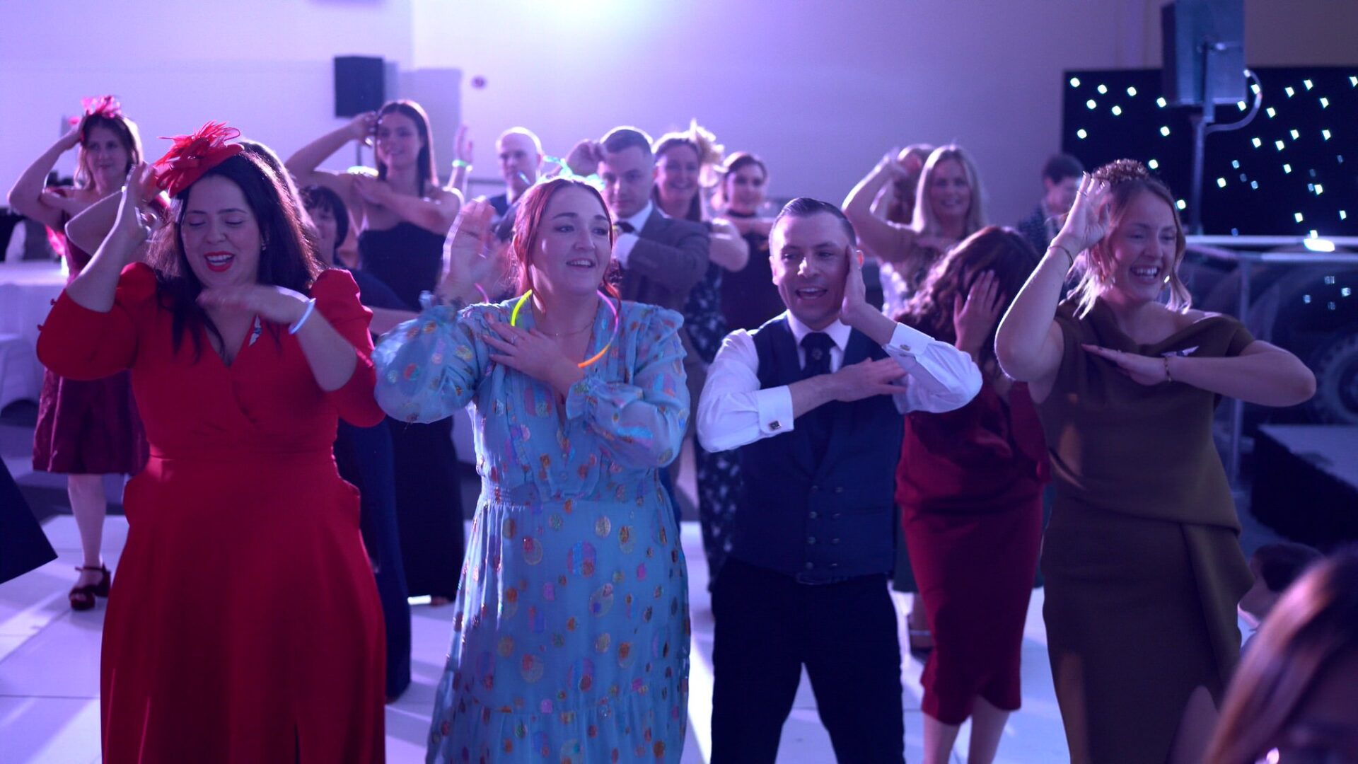 a groom dances the macarena with his friends at his wedding