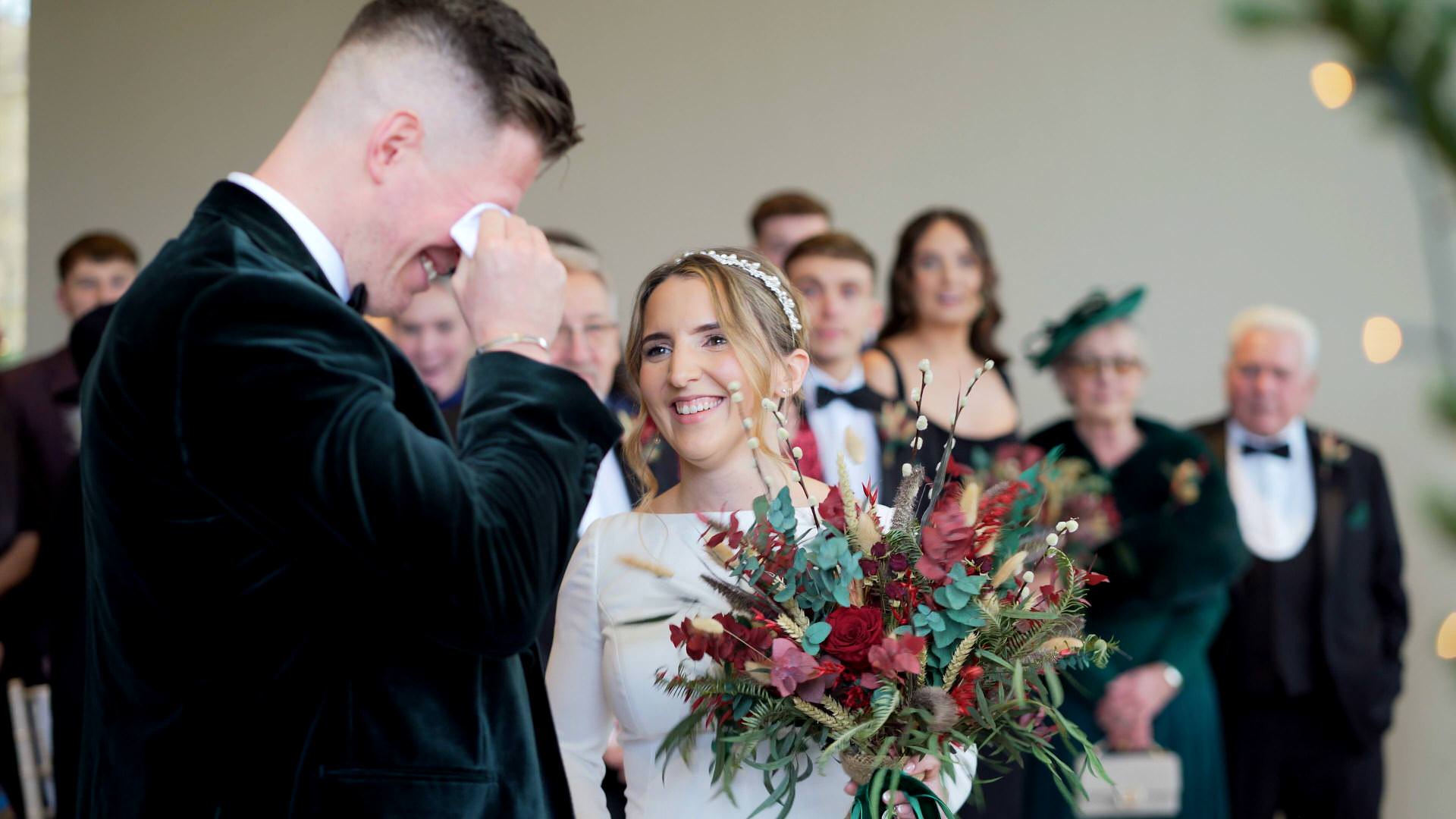 an emotional groom wipes away his tears during ceremony at the Out Barn