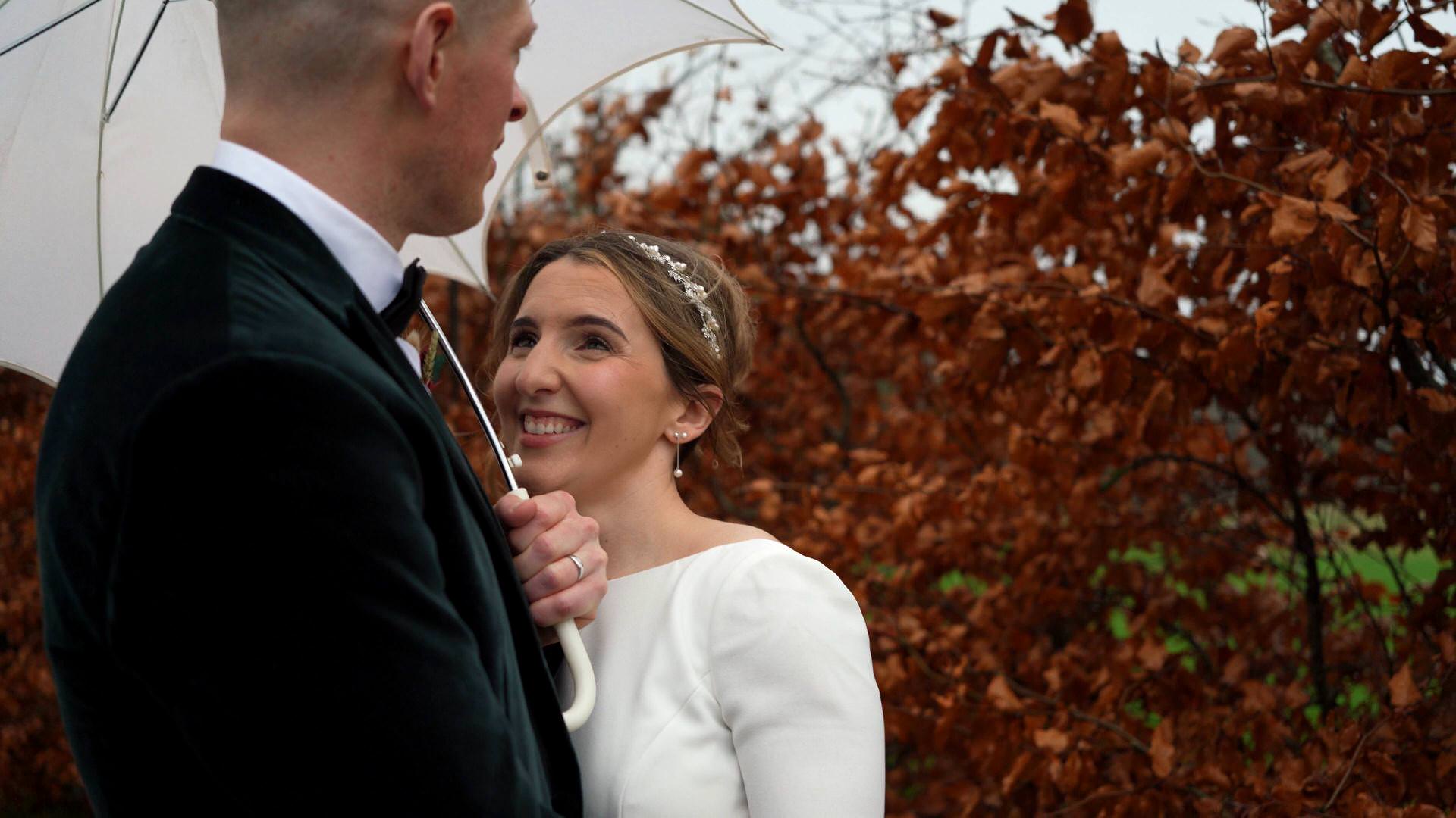 a couple shelter from the rain during their wedding at the Out Barn
