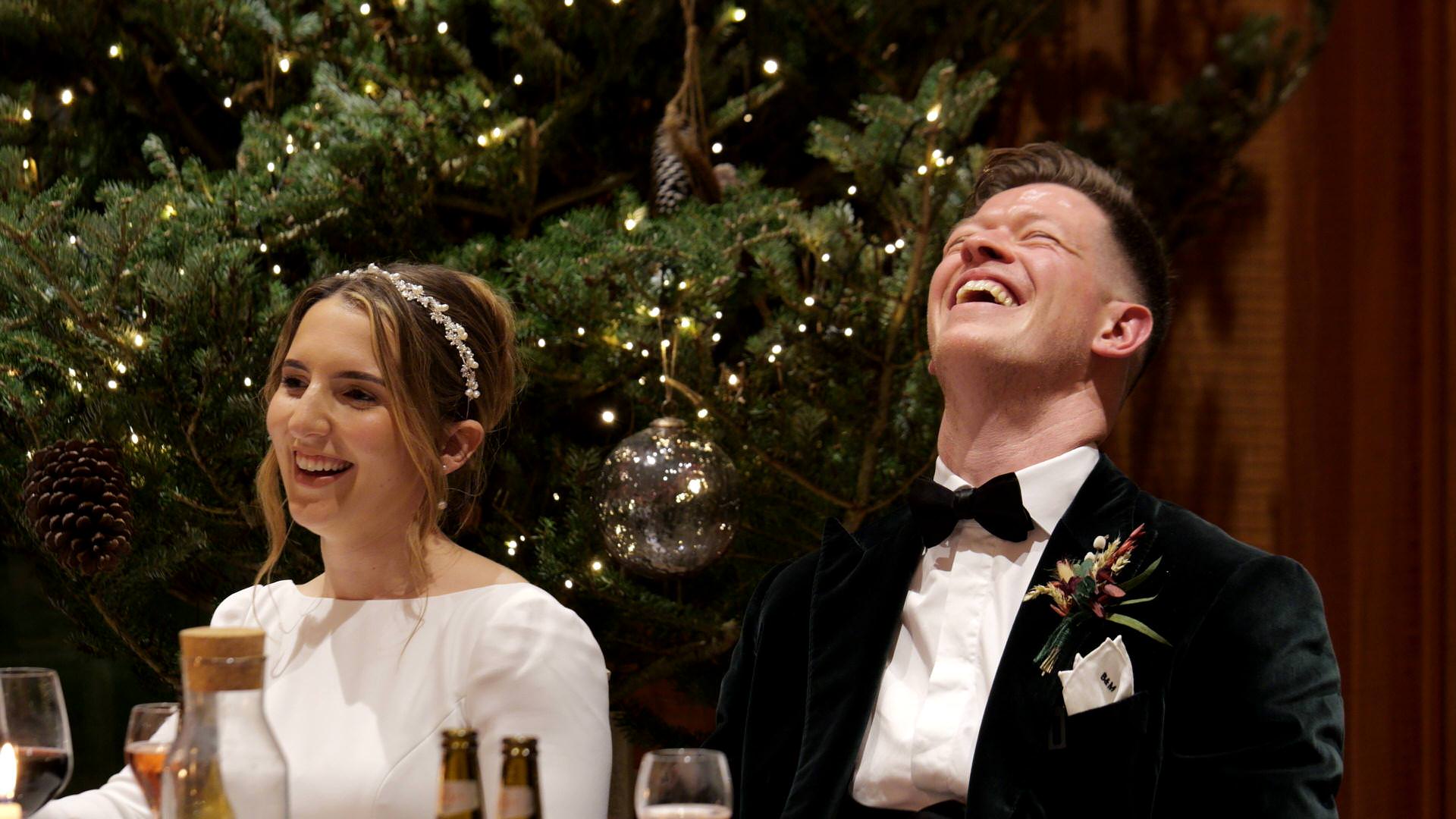 the groom laughs at his best mans joke during speeches