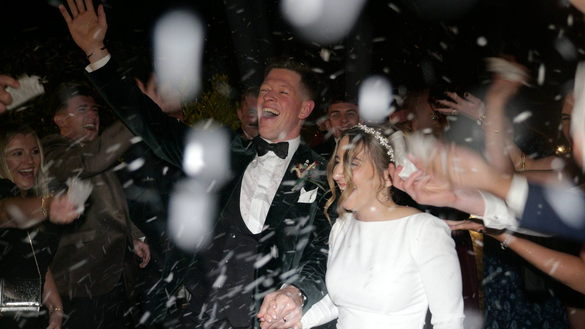 a close up of a couple having fun in the rain with snowfetti outside the Out Barn