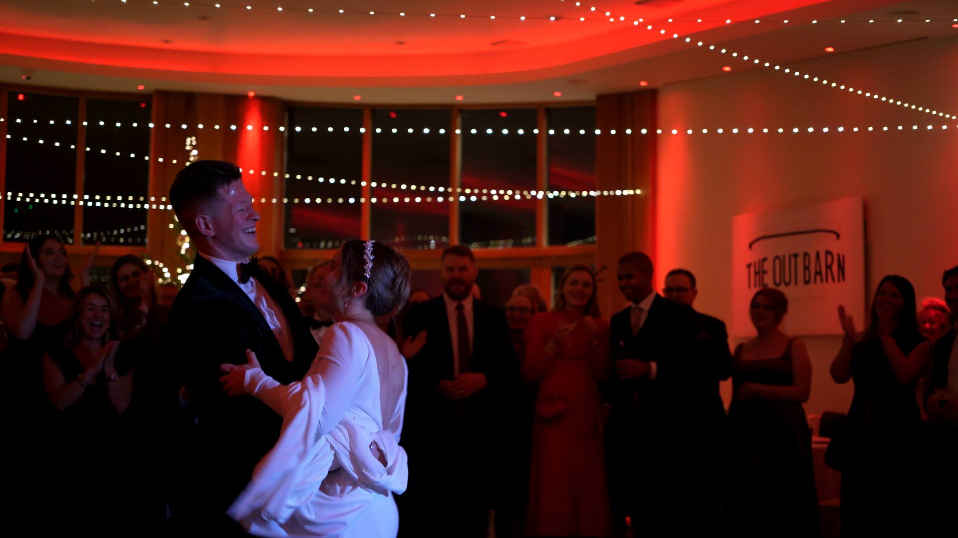 videographer captures guests singing along with the couple during first dance at the Out Barn
