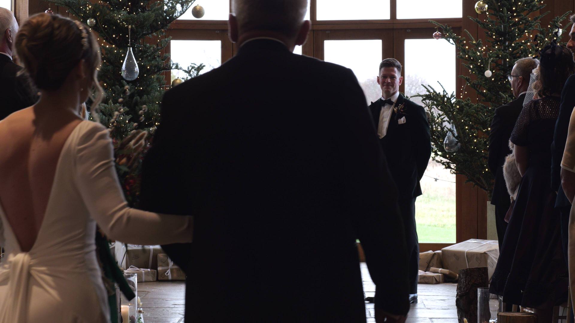 a wedding videographer films the brides walks down the aisle at the Out Barn
