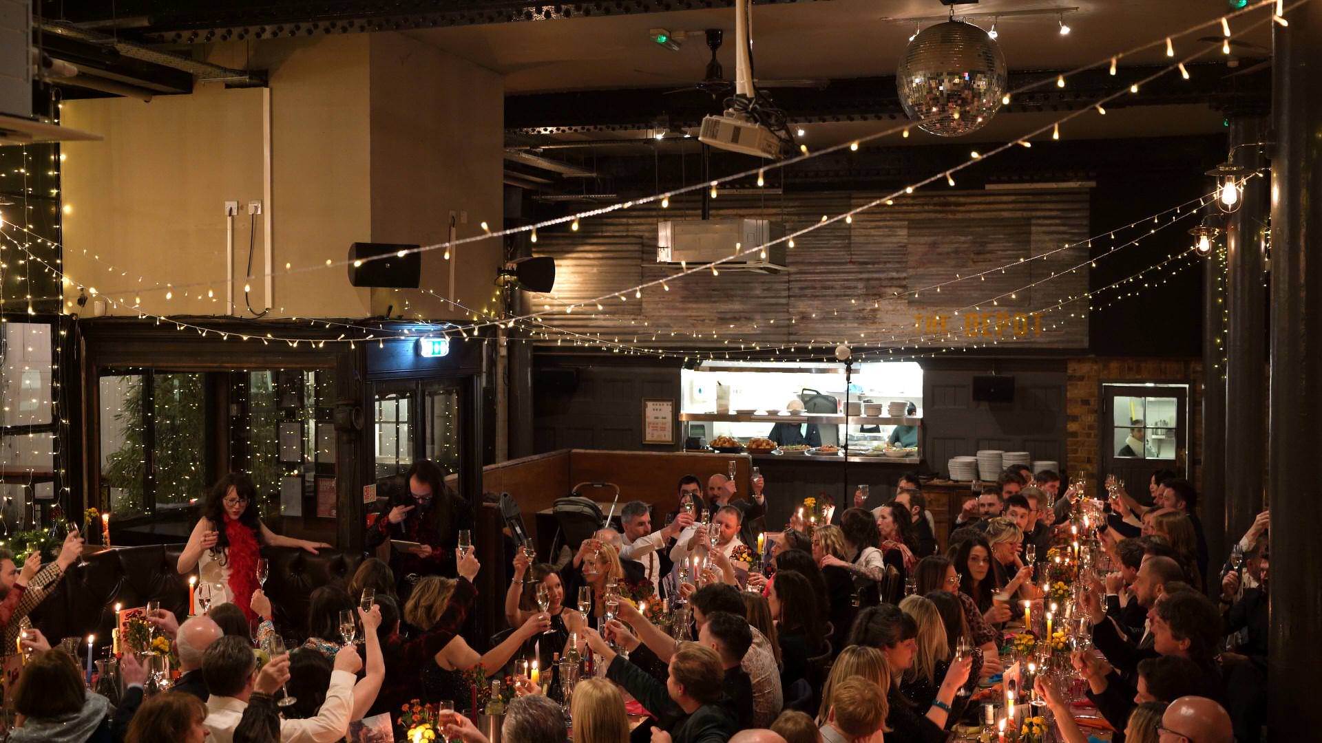 a wide shot of the whole room raising a toast during the wedding reception at a city wedding