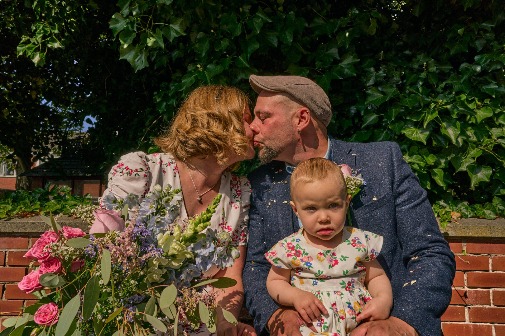 a couple kiss for the wedding photographer in summer sunshine outside Ormskirk registry office