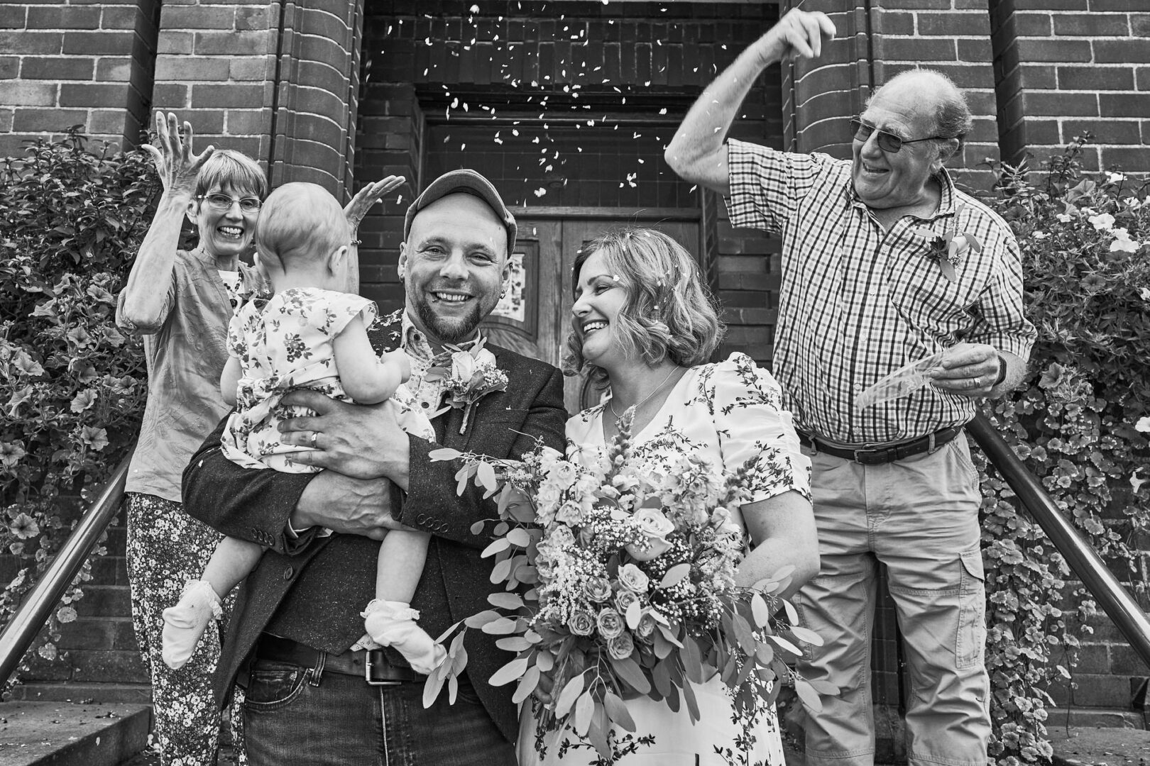 an intimate elopement ends in confetti outside a couple get ready to walk down the aisle and wave to their toddler in Ormskirk