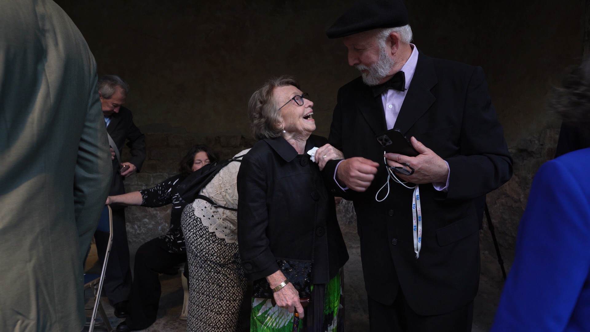 two elderly guests laugh together during drinks reception