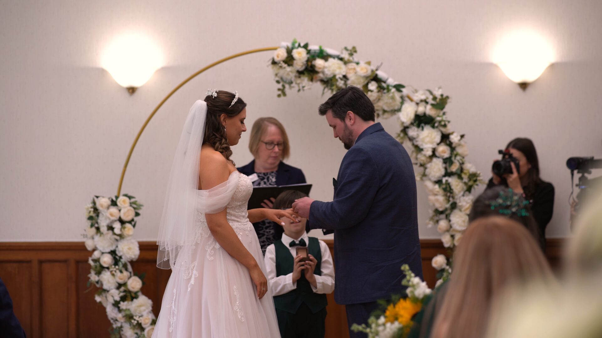 a couple exchange rings as their young song ring barer looks on at Wyre Civic Centre
