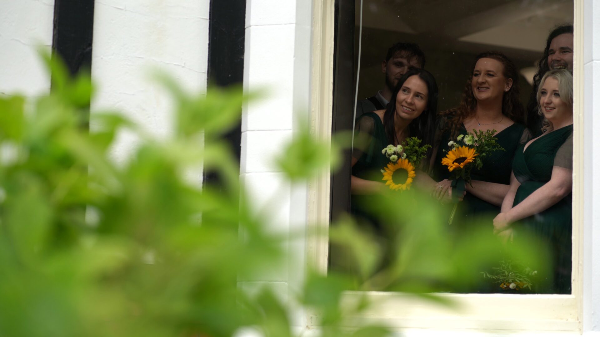 a unscripted moment of bridesmaids looking out the window of Wyre Civic Centre to watch the couple in the gardens