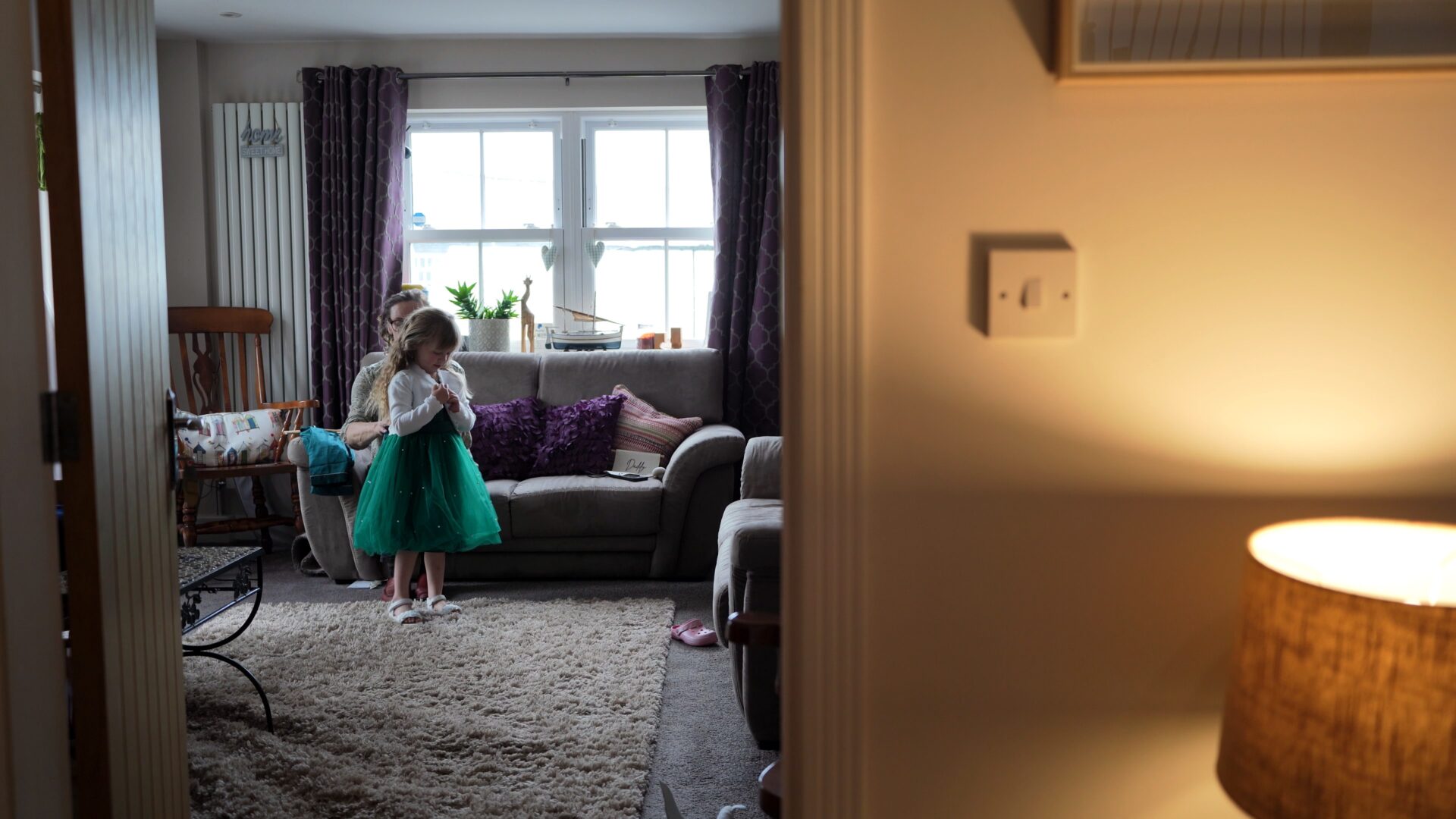 videographer captures a candid moment of nana helping the flowergirl into her dress on the wedding morning