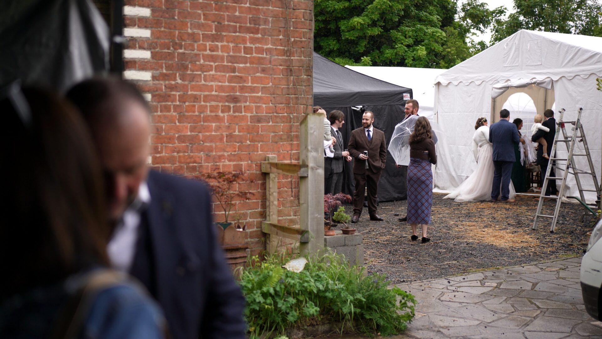 wedding guests stand with umbrellas at a DIY wedding in Lancashire