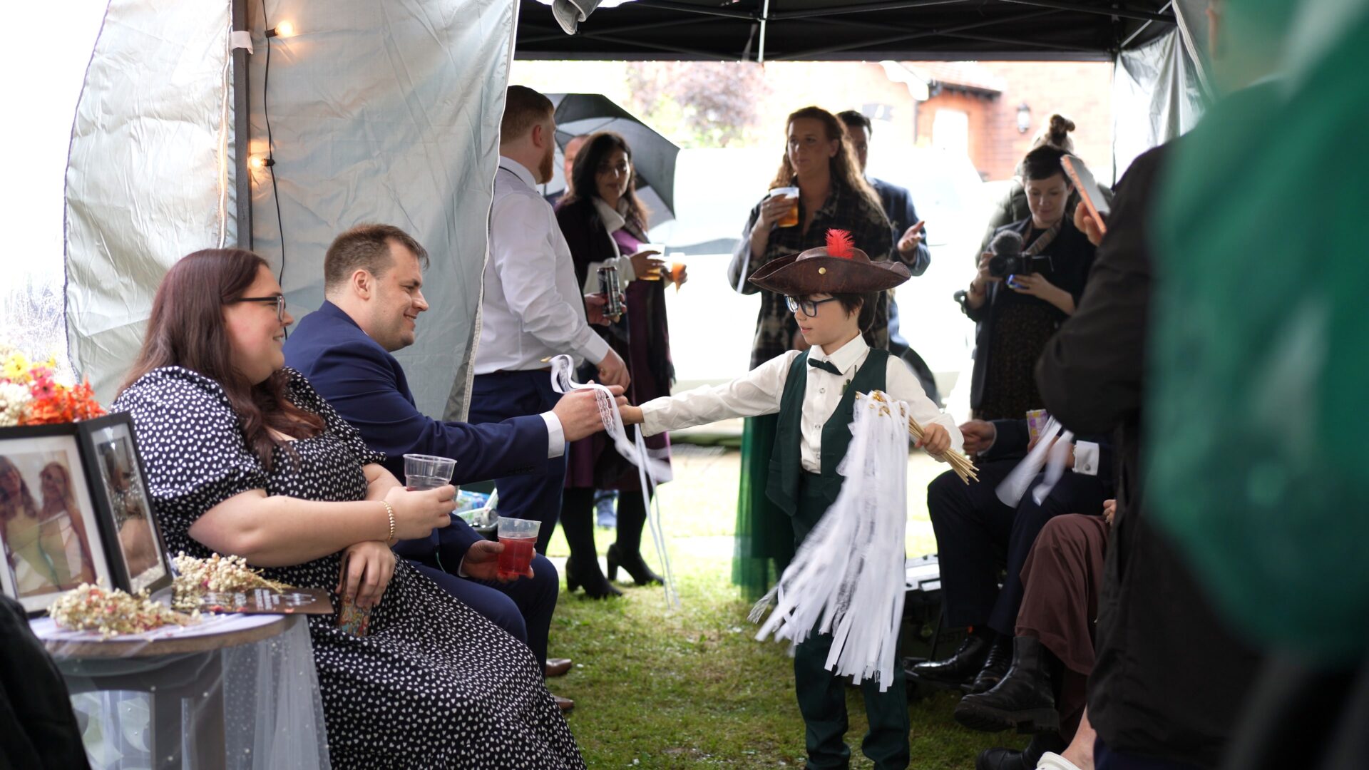 a page boy in a pirates hat hands out white lace wands for guests