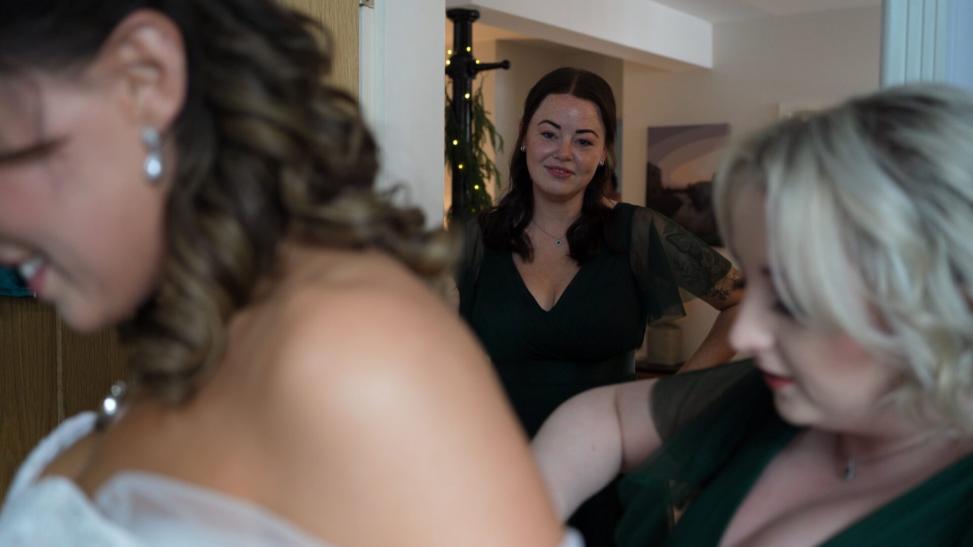 a bridesmaid looks on at the bride gets into her wedding dress