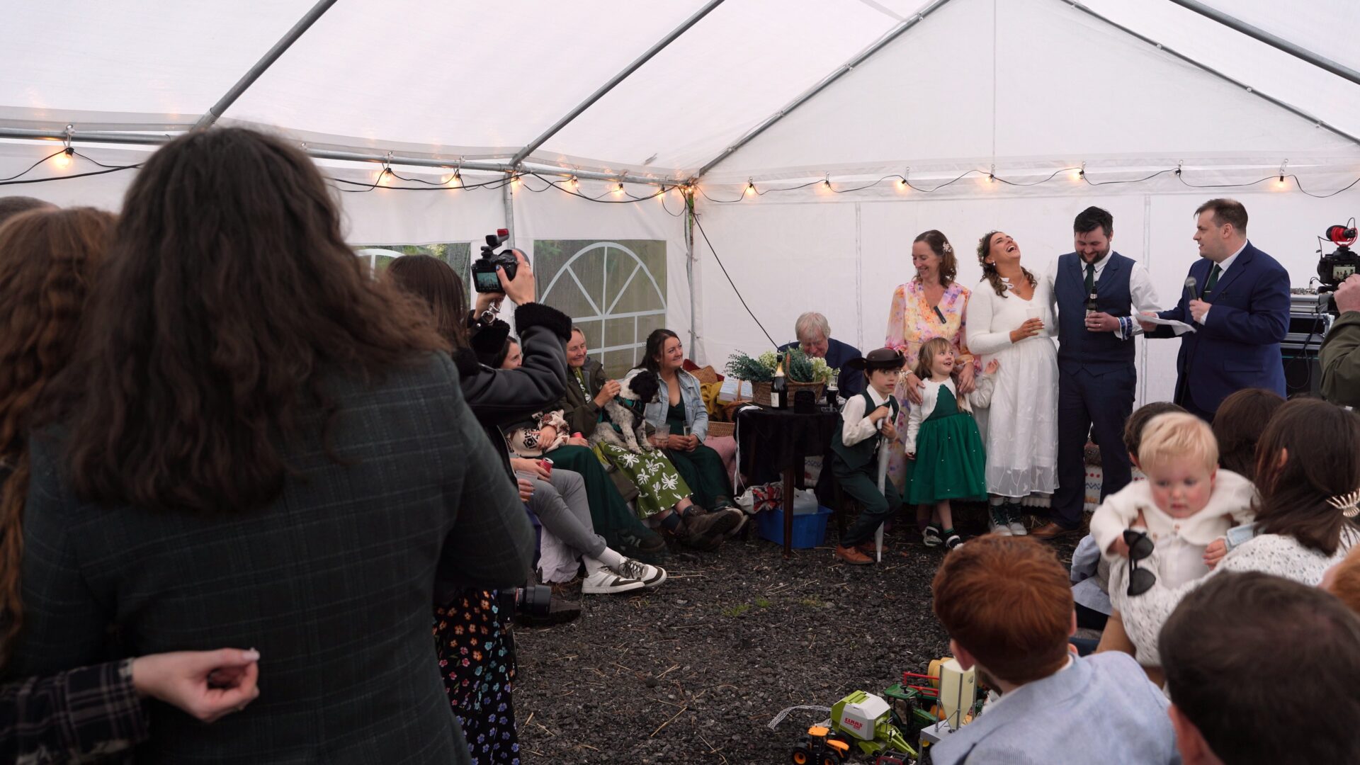 the couple laugh along during the wedding speeches inside a DIY marquee wedding