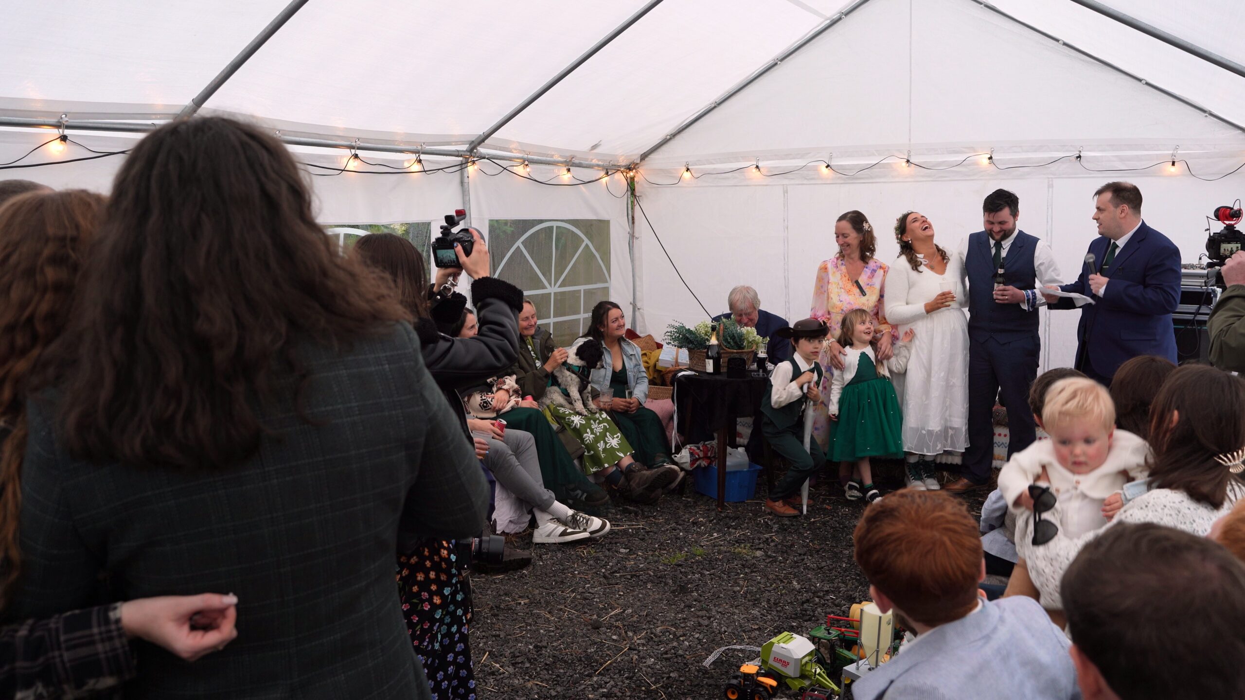 the couple laugh along during the wedding speeches inside a DIY marquee wedding