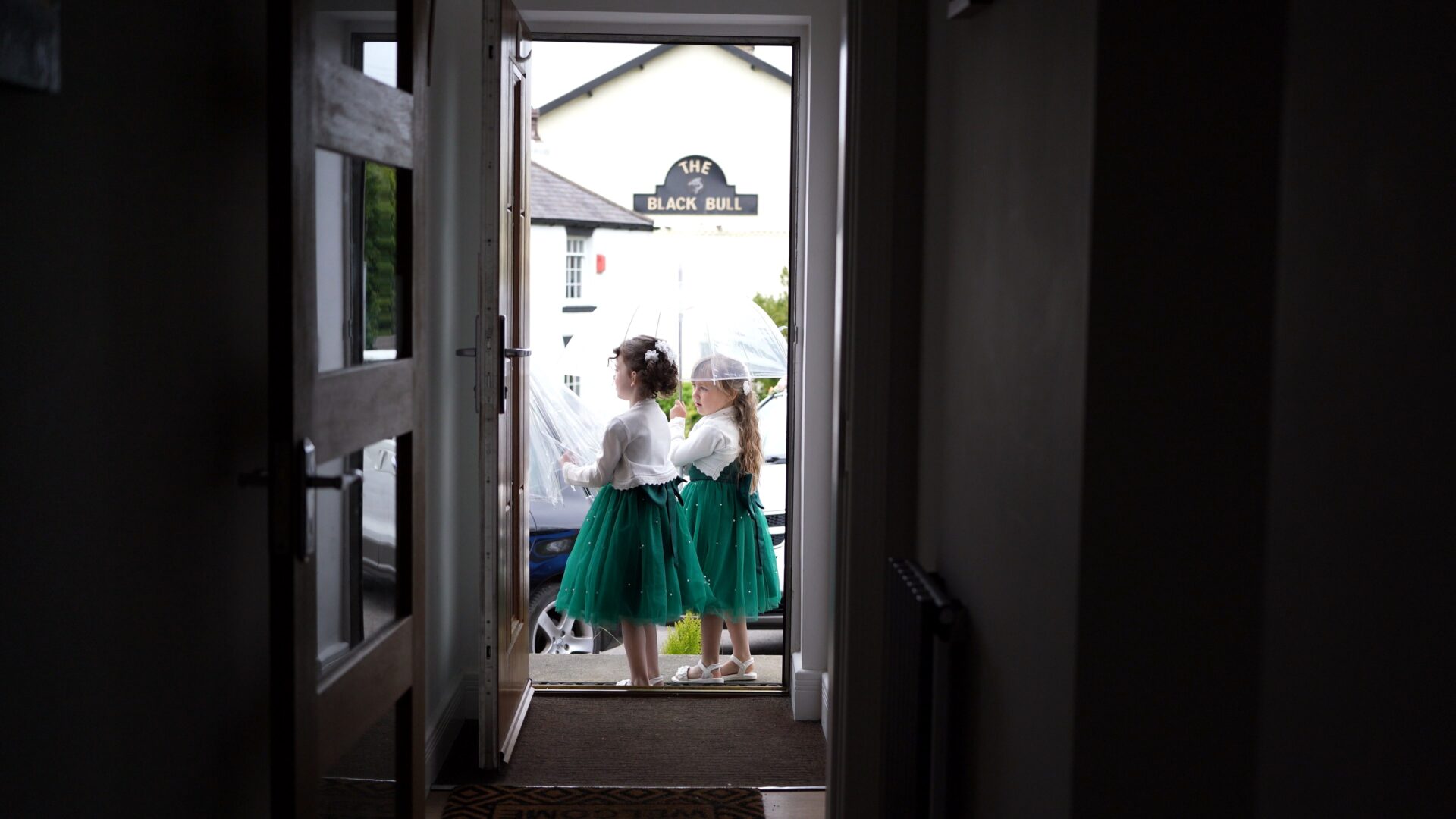 two flower girls test out their wedding umbrellas in the rain