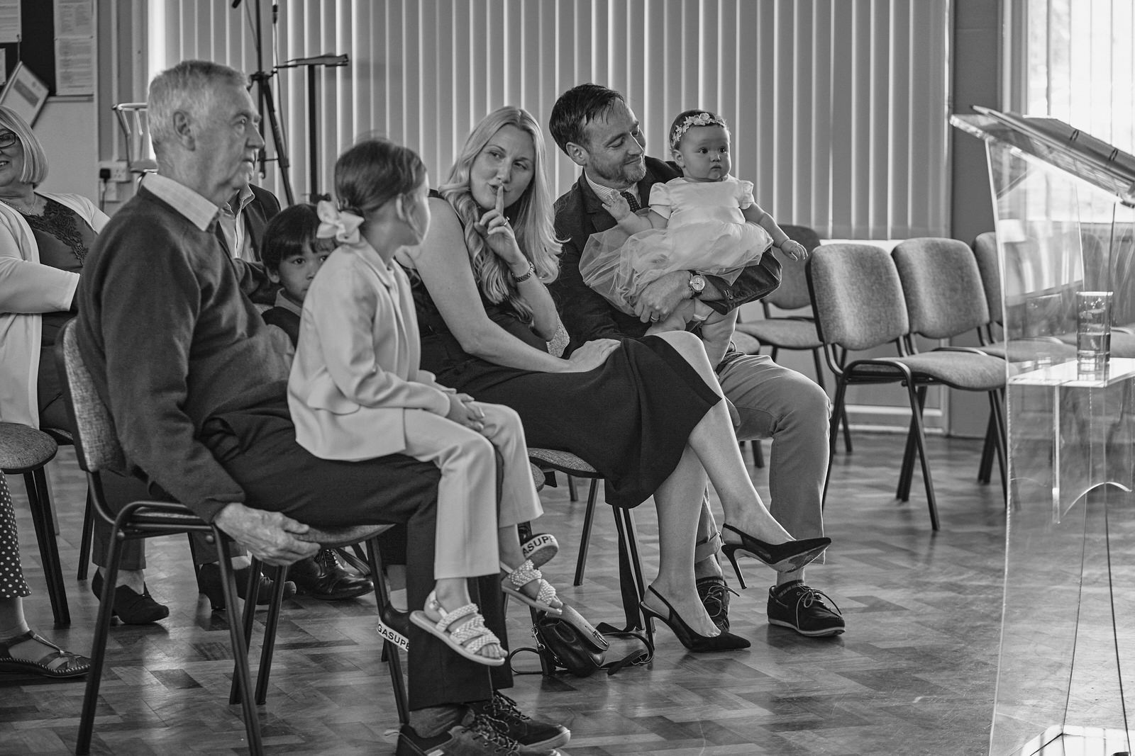 a mum puts her finger up to shush children during christening