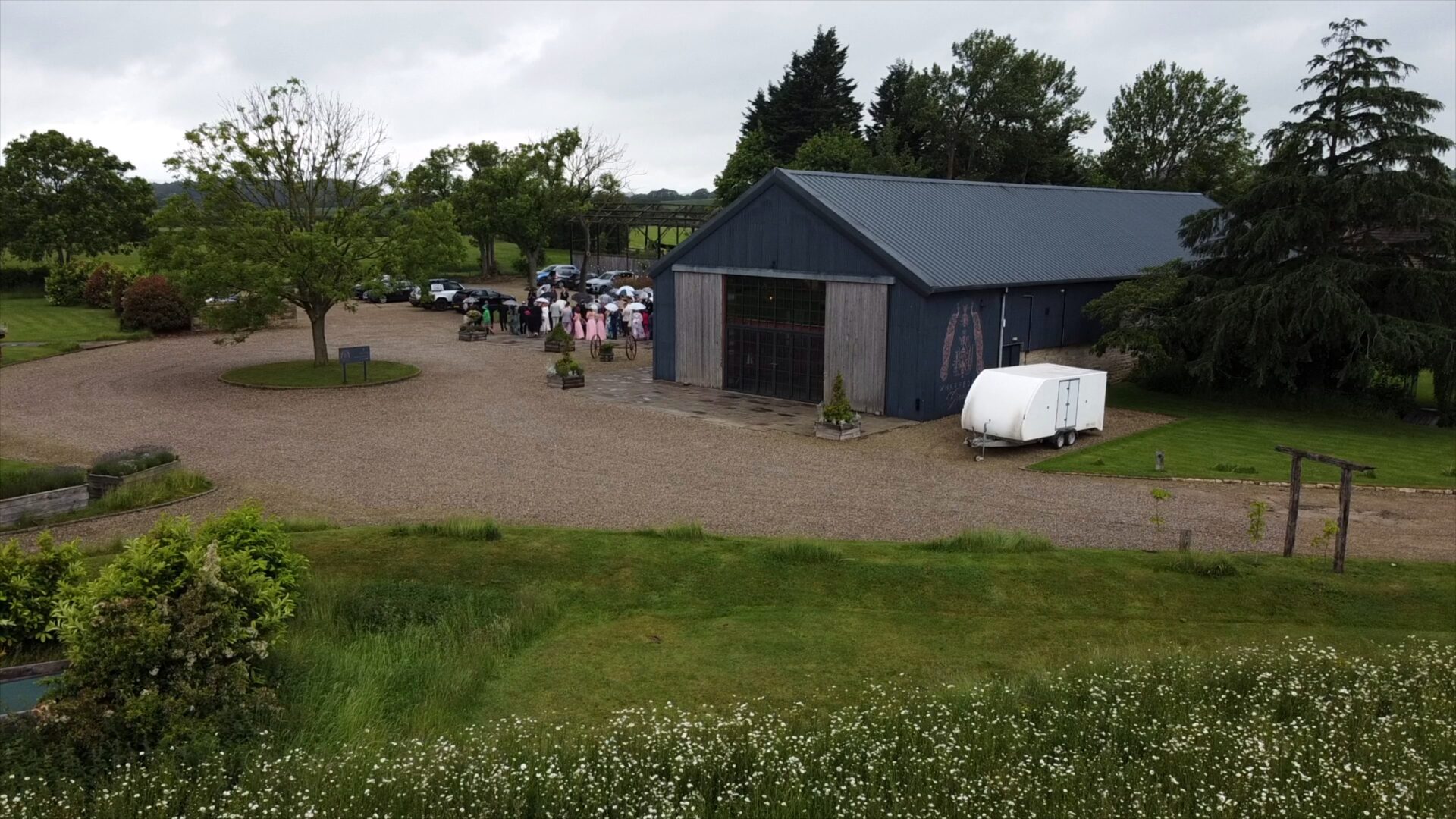 a wide drone shot of the couple arriving in a vintage car outside Wharfdale Grange in the rain