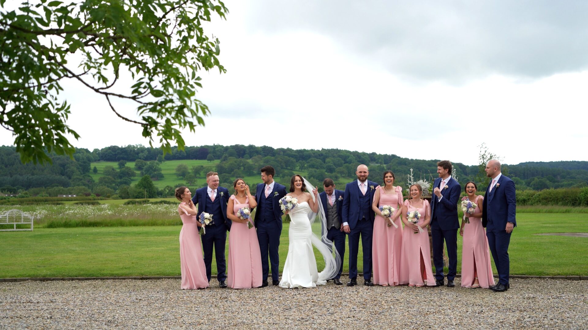 the bridal party laugh as they try to pose for their wedding photographer in the luxury grounds of Wharfedale Grange