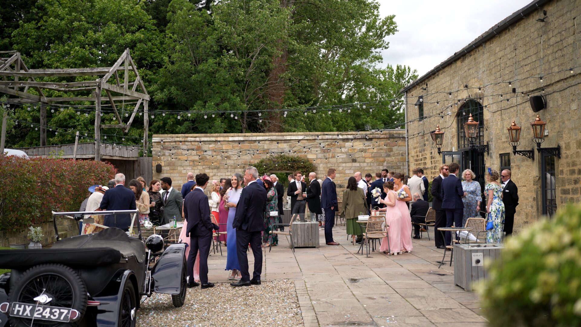a wide video shot of the guests enjoying drinks on the patio outside the luxury barn at Wharfedale Grange