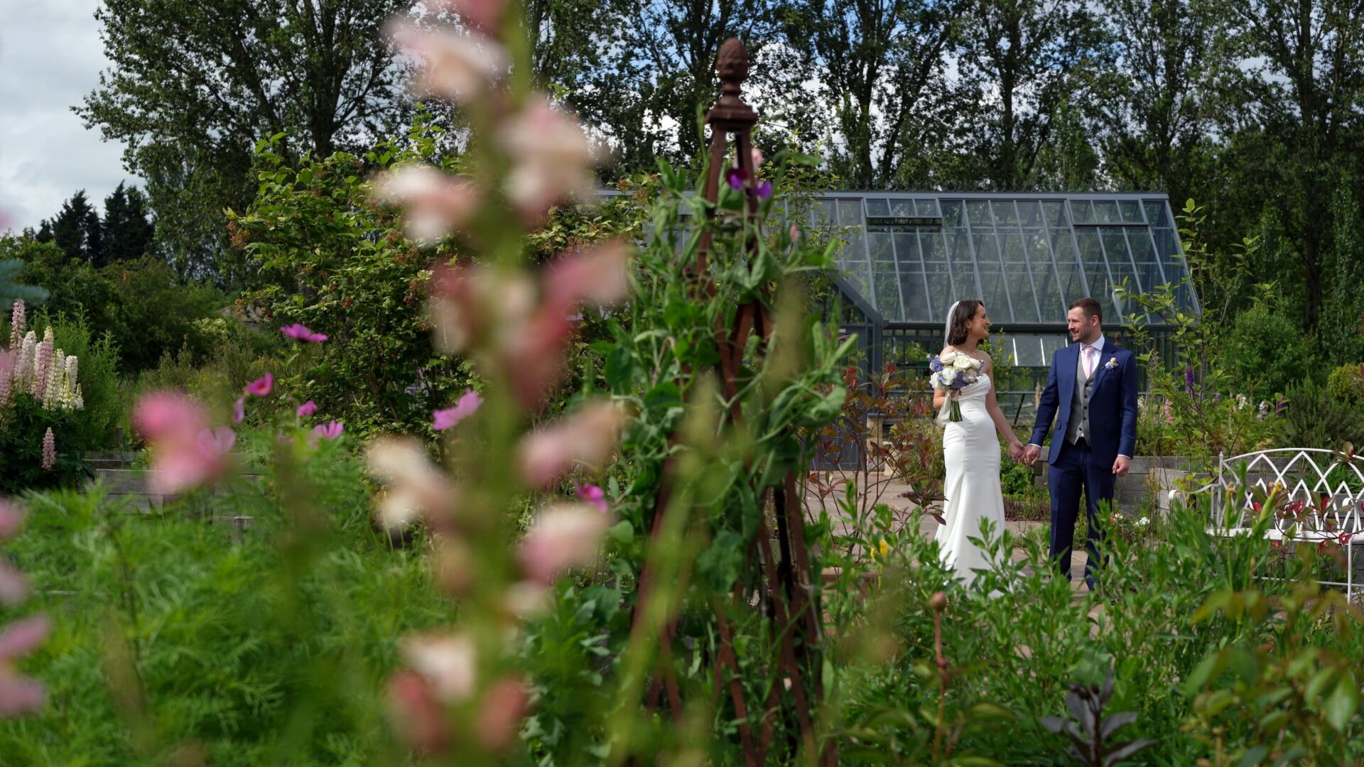 a candid documentary wedding videographer captures the couple laughing and enjoying the flower cutting glasshouse at Wharfedale Grange in Yorkshire