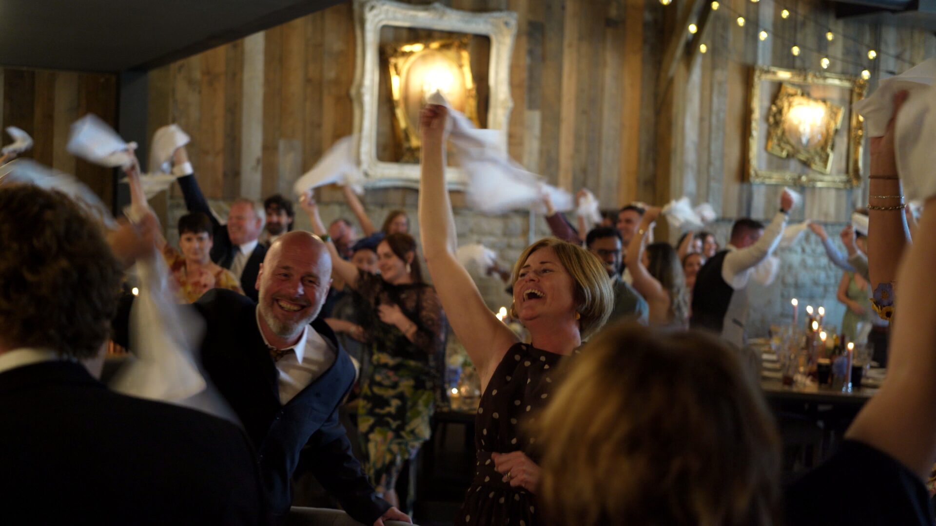 Candid documentary style wedding videography of the high energy guests give during the couples entrance to Wharfedale Grange waving napkins ahead of their wedding breakfast