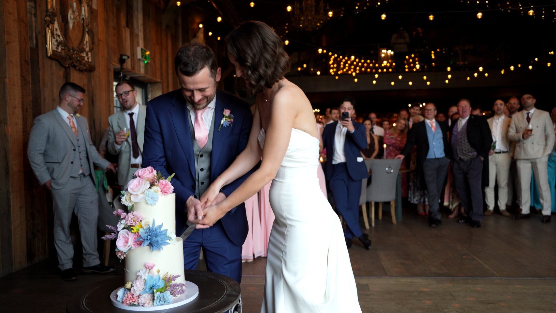 a natural light wedding video moment of the cake cutting where you can see all the guests in the background