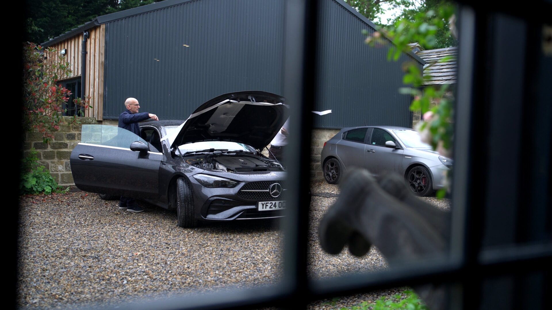 Candid documentary style wedding videography of a Dad and Groomsmen adding ribbon to the luxury wedding car during a rainy morning prep at Wharfedale Grange.