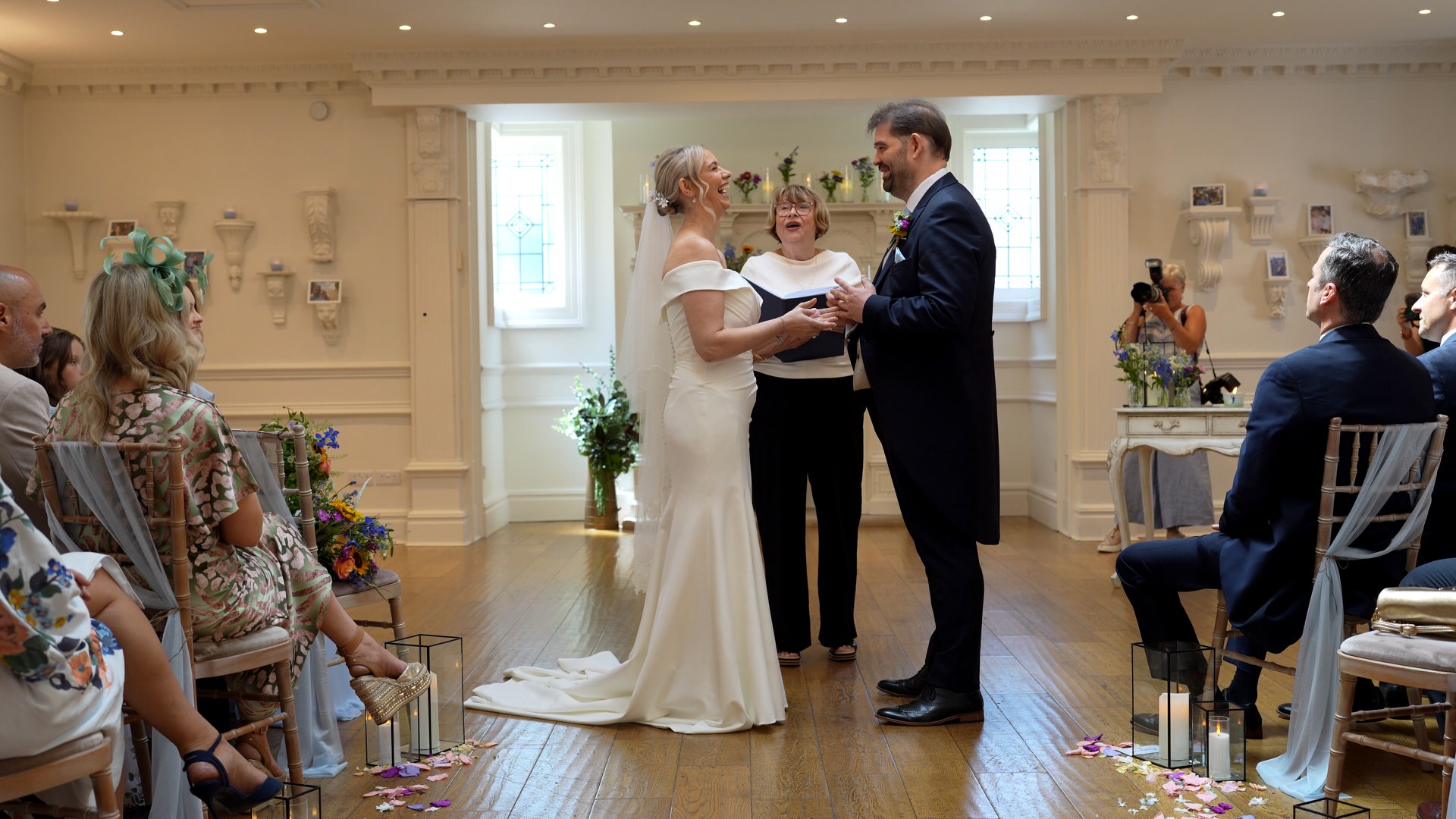 a wedding videographer captures the couple laughing as they exchange wedding rings at Ashfield House
