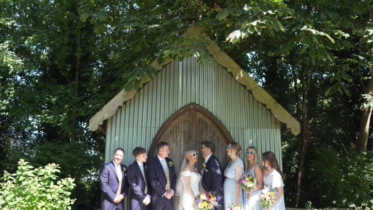 the bridal party laugh for the photographer as the videographer captures the behind the scenes moments