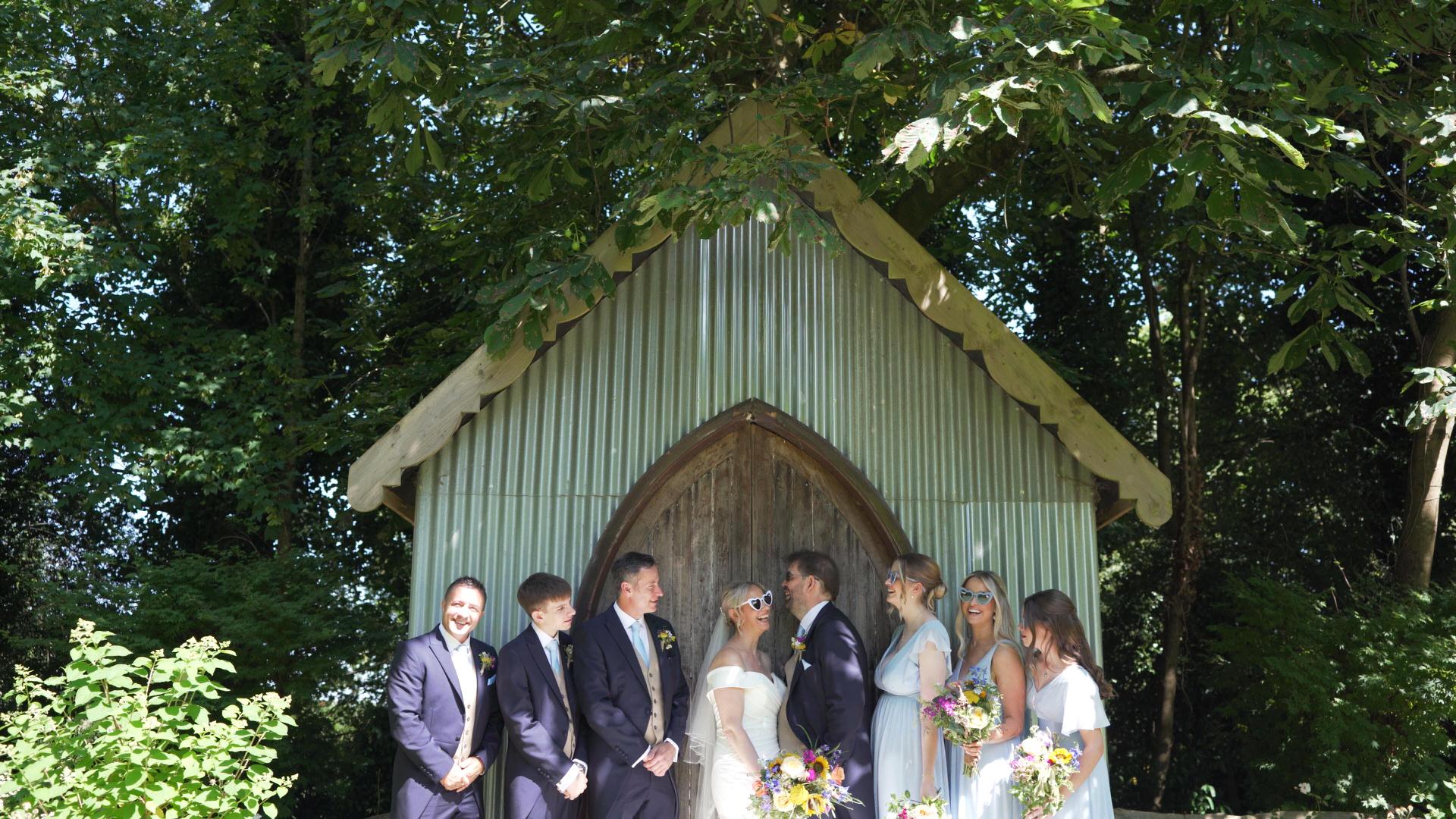 the bridal party laugh for the photographer as the videographer captures the behind the scenes moments