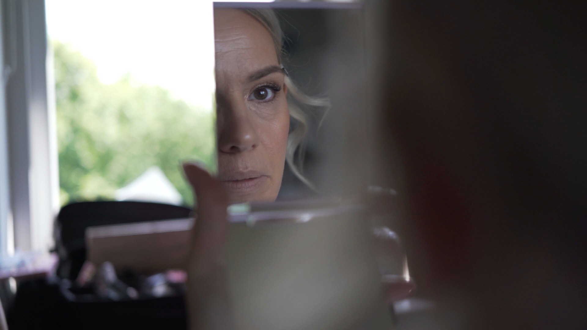 a bride looks into her makeup mirror to check her final bridal look at Ashfield House