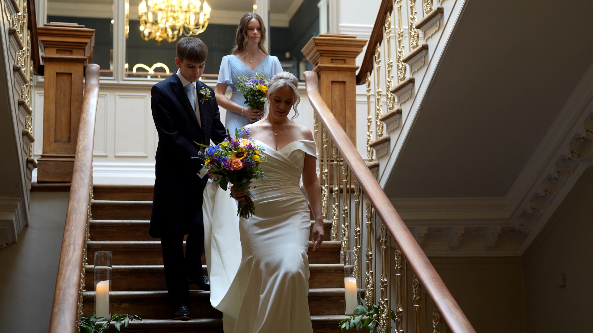 the bride and her son make their way down the staircase at Ashfield House